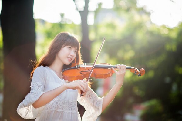 Orientale ragazza in abito bianco suona il violino