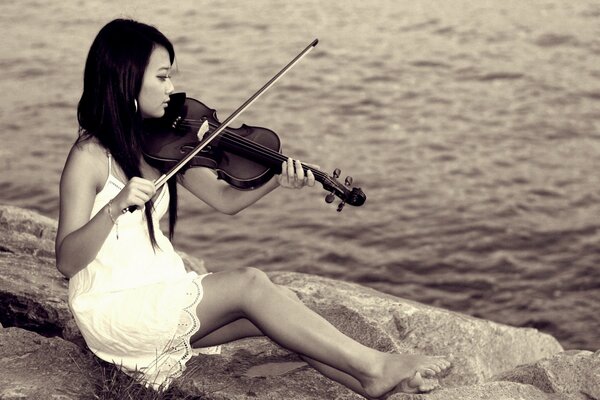 Ragazza asiatica che suona il violino sullo sfondo della superficie dell acqua