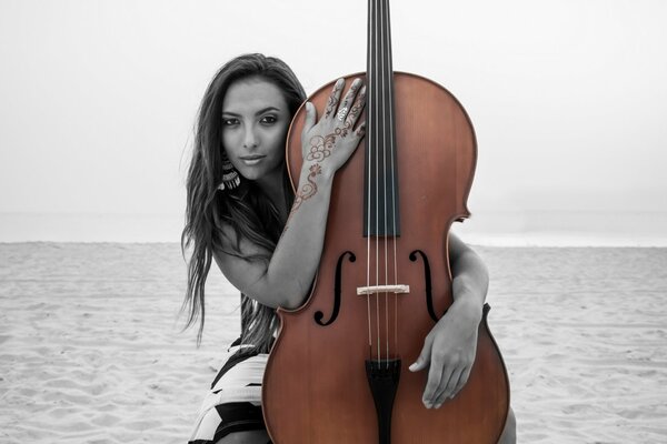 Chica en la arena abraza contrabajo