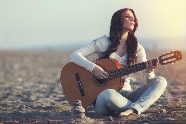 A girl with a guitar on the background of the setting sun