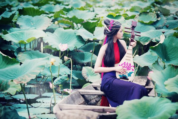 Asian girl on the lake playing in a boat. Thoughtful look