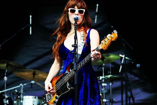 Famous girl singer Jenny Lewis standing on stage and playing guitar