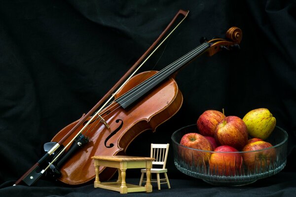 Скрипка , стол со стулом и тарелка с яблоками