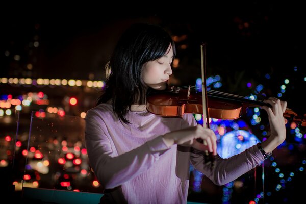 Fille jouant du violon sur le fond de la ville de nuit