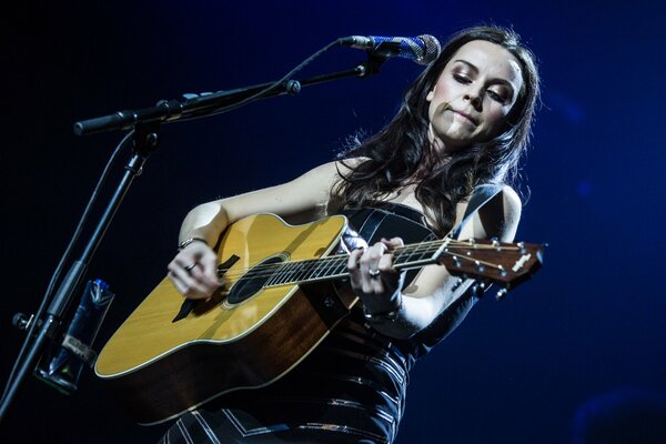 A girl plays guitar at a concert