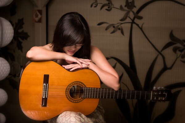 Das Mädchen sitzt und umarmt die Gitarre