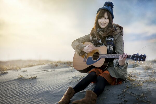 A girl in a hat plays an acoustic guitar