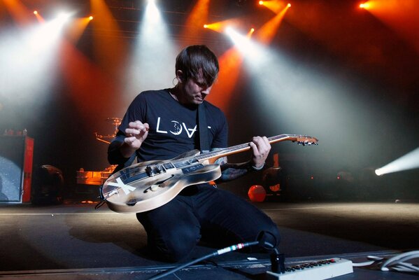 Tom delong on his knees playing guitar