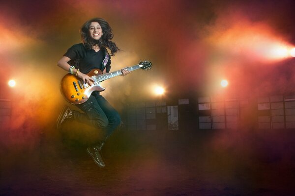 A girl in jeans plays the guitar