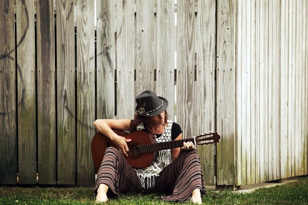 Jeune guitariste au chapeau près de la clôture