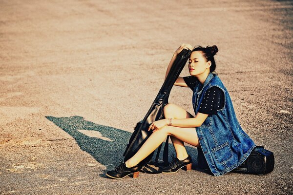 A girl on the street with a guitar and a tape recorder