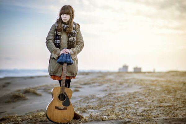 A girl with bangs stands holding onto a guitar