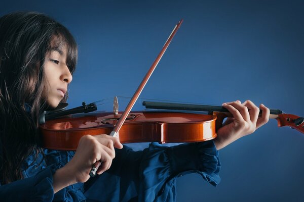 A girl plays the violin on a blue background