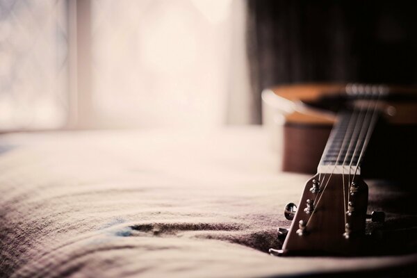 The guitar is lying on the bed