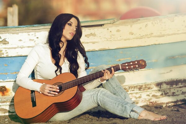 Ragazza con chitarra seduta sulla sabbia