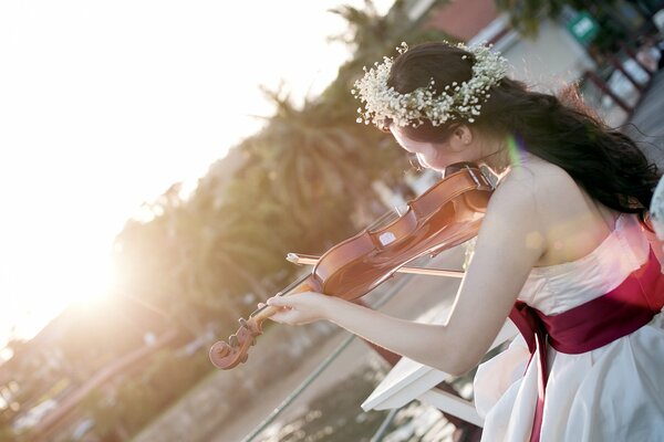 A girl in a flower wreath plays the violin