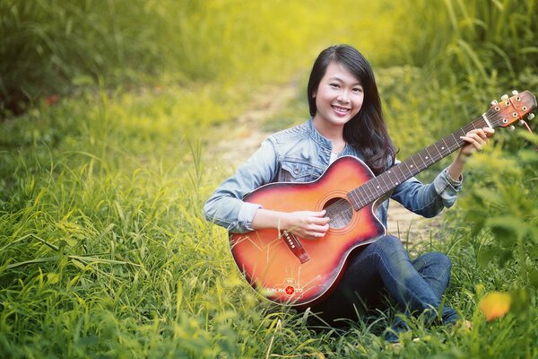 Gitarrenlieder auf einer grünen Lichtung asiatische Mädchen