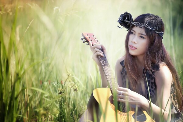 Chica asiática con la guitarra en el campo