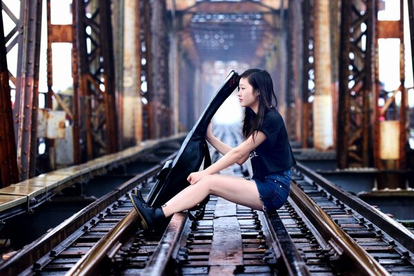 The girl is sitting on the railway tracks