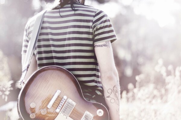 A musician with a guitar with tattoos on his hands