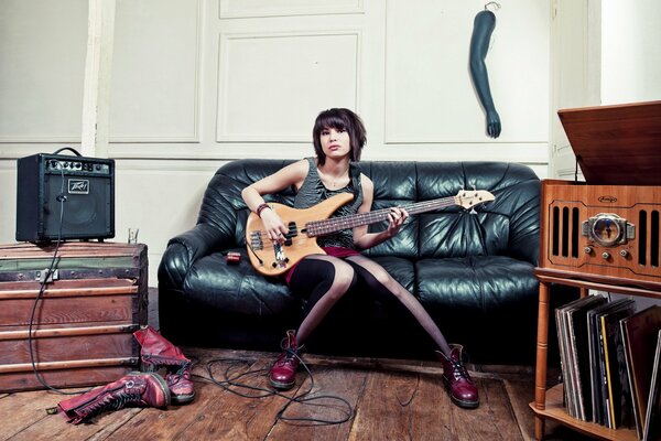 Fille avec une guitare sur le canapé