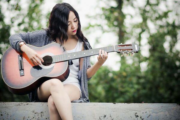 Hermosa chica tocando la música en la guitarra