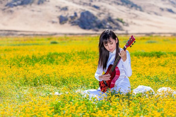 A girl with a red guitar in the field