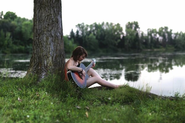 Девушка с гитарой на берегу озера