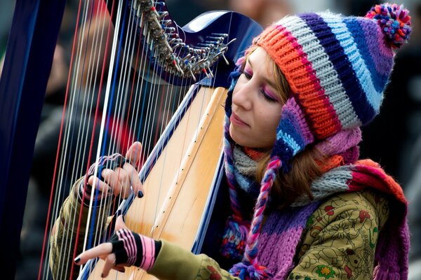 A girl plays a harp with a multicolored hat