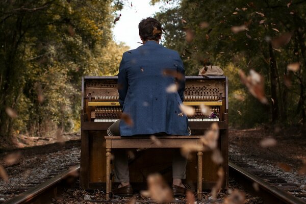 Sullo sfondo di un paesaggio autunnale, un ragazzo suona il piano