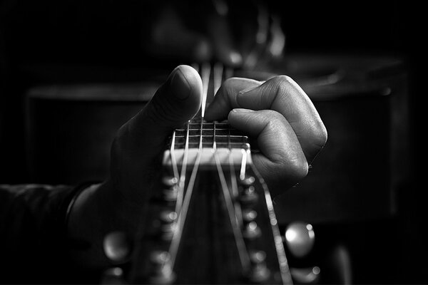 Die Finger drücken die Saiten der Gitarre zusammen