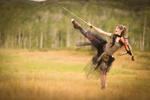 Chica bailando en el campo con el violín