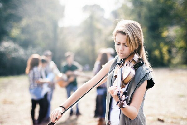 Chica adulta tocando el violín en el fondo de la gente