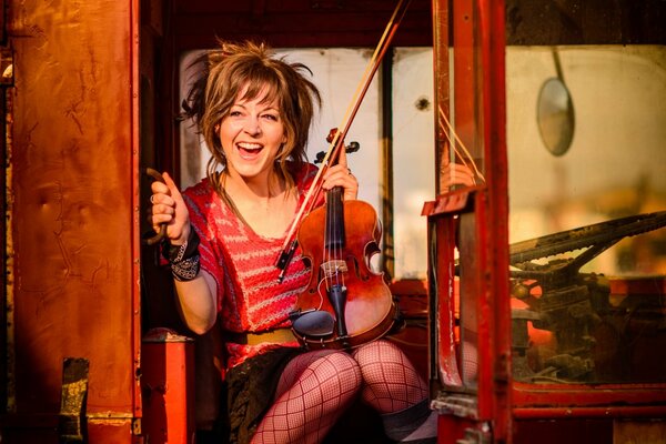 Lindsey Stirling mit einer Geige im roten Bus