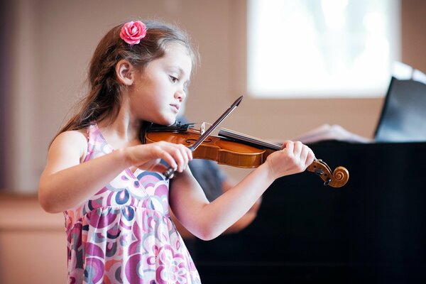 Bambina in abito floreale rosa che suona il violino