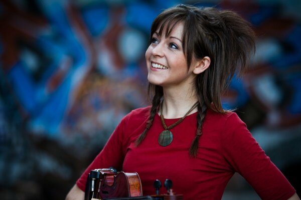 Lindsey Stirling con un violino contro un muro di graffiti