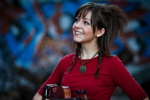 Линдси Стирлинг со скрипкой у стены с граффити