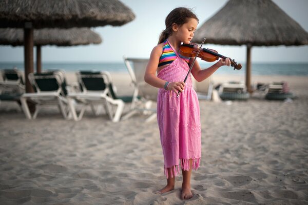 Petite fille en robe rose joue du violon