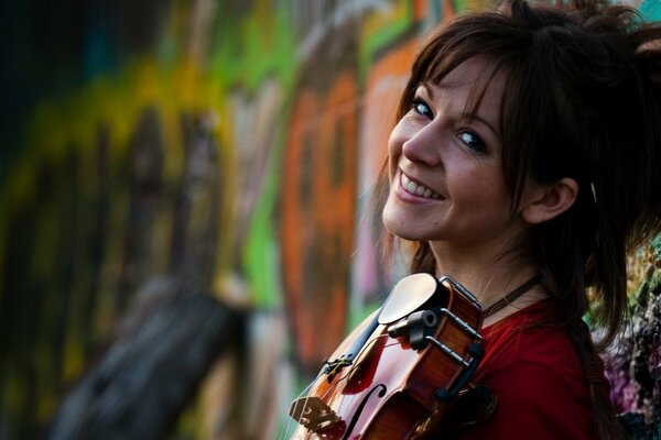 Smiling girl on the background of graffiti with a violin