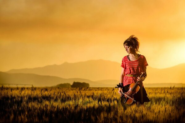 Skrzypaczka Lindsey Stirling w polu na tle zachodu Słońca