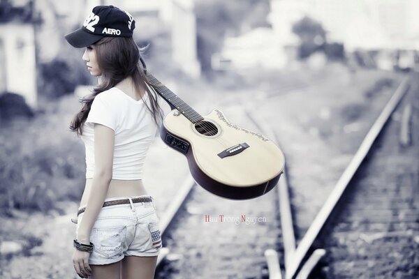 A girl with a guitar on the train tracks