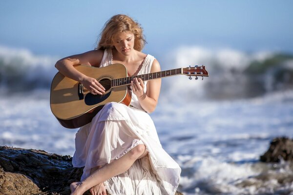 MÄDCHEN SPIELT GITARRE AM MEER