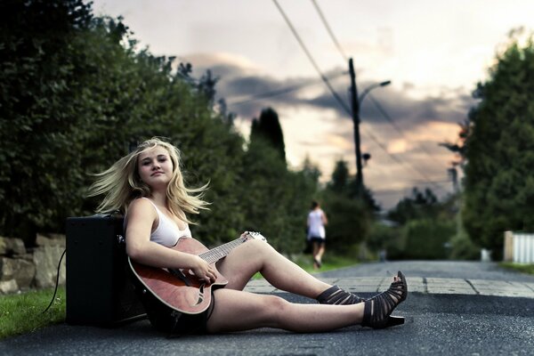 A girl at sunset with a guitar in her hands