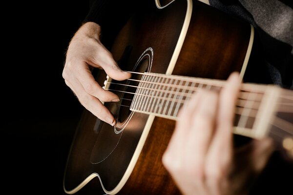 Manos en las cuerdas de la guitarra acústica