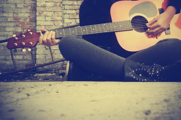 Ragazza si siede e suona la chitarra