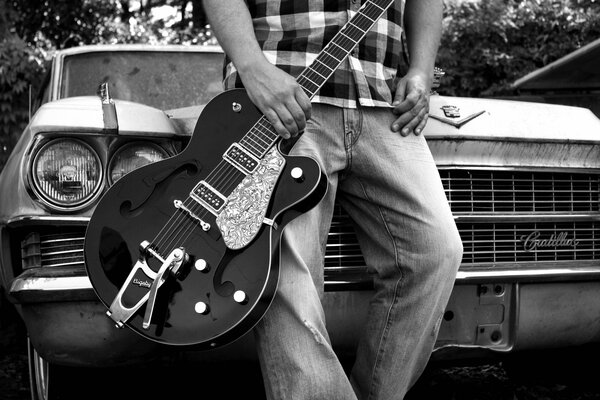 Retro car. A guy with a guitar on the background of a car