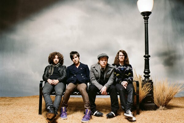 The band fall out boy on a bench under a lantern