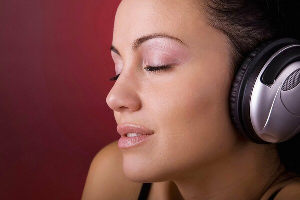 Девушка слушает музыку в наушниках с закрытыми глазами