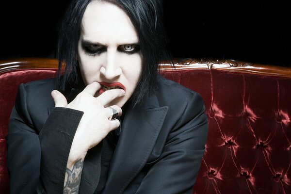 Marilyn Manson on a red velvet sofa