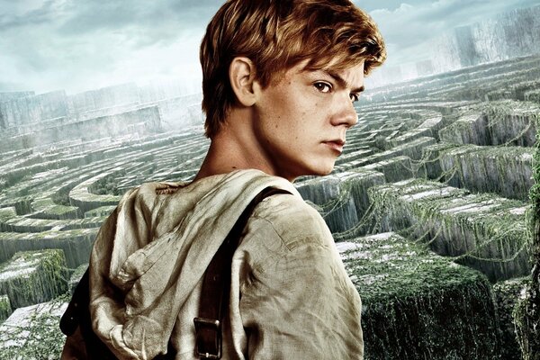 Thomas Brodie-Sangster sullo sfondo di un labirinto ricoperto di piante